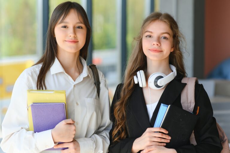 Education. Two clever modern students in black and white uniform study in a library sitting at a table with books. Modern generation. Students